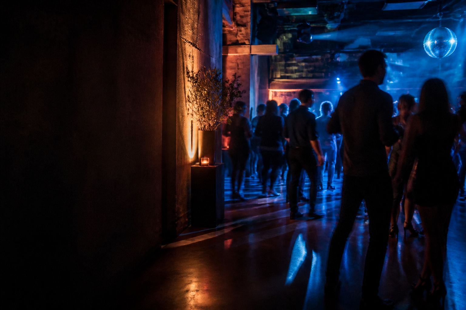 A contemporary event room with anonymous guests under controlled blue and warm lighting